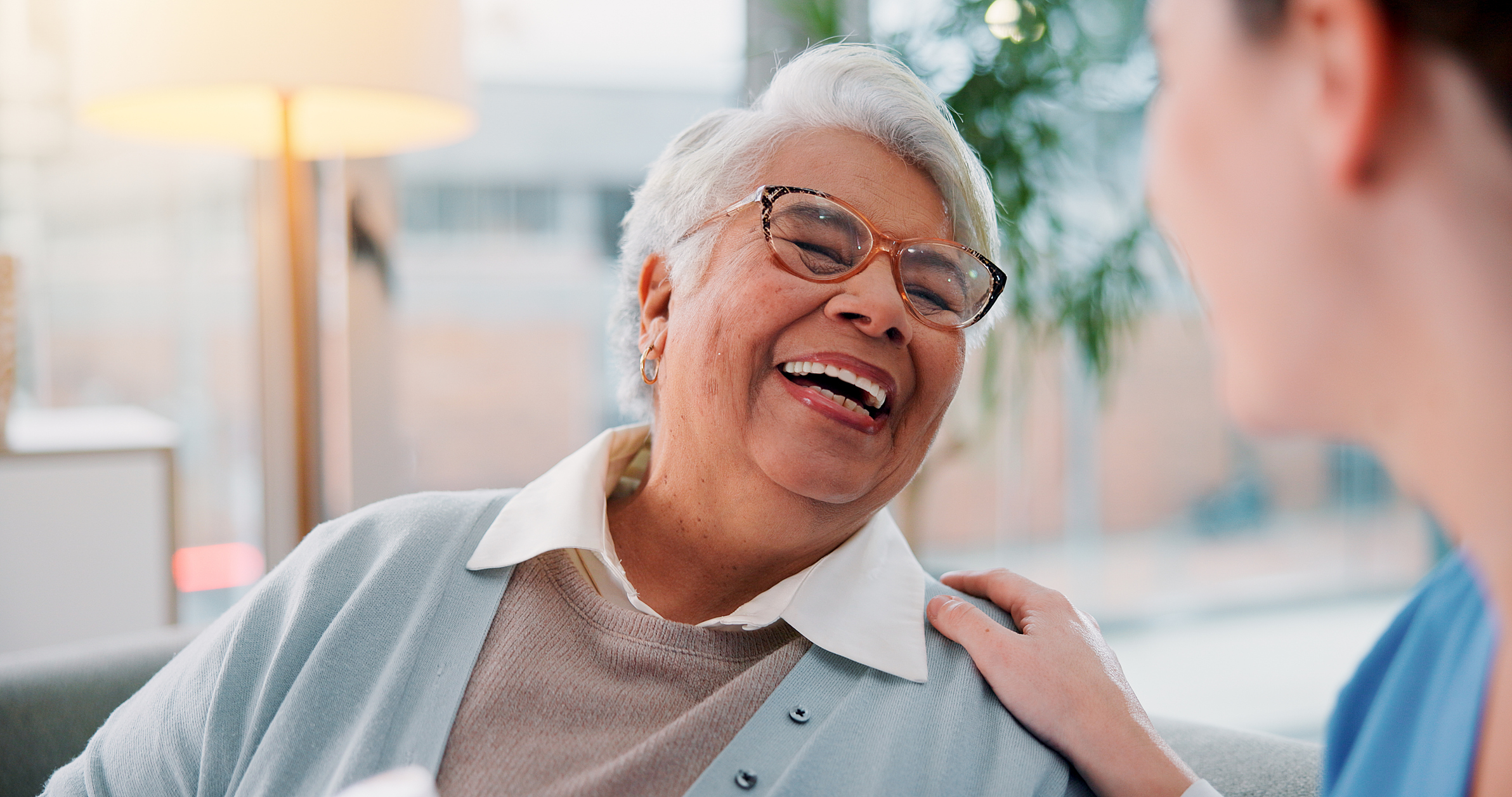 Elderly woman, nurse and laughing in home for funny conversation, healthcare advice and empathy. Senior patient, caregiver and happy for homecare assistance, kindness and medical help in retirement